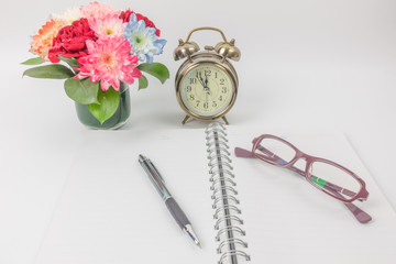 Watch vintage with notebook ,pen ,glasses and flower vase on whi
