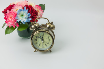 Vintage alarm clock and flower vase on white background