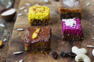 Four pieces of different raw cakes on wooden brown board