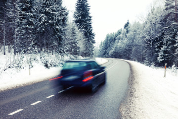 Lonely car in motion blur on the road in winter landscape