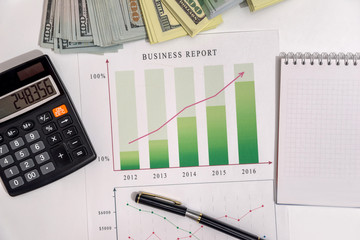 Pen on graphs business report with money
