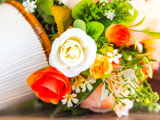 A bouquet of white and orange roses Artificial Flowers in a vase .