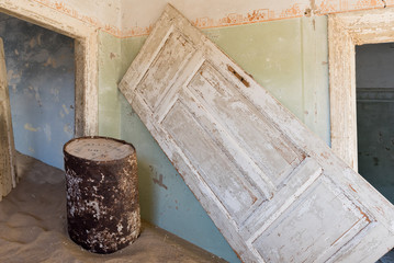 Raum mit Fass und umgekippter Tür in Kolmanskop, Namibia