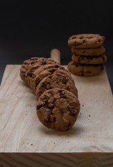 Chocolate cookies on a wooden cutting board. Black background.