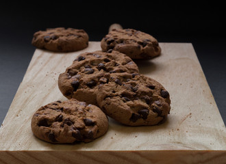 Chocolate cookies on a wooden cutting board. Black background.