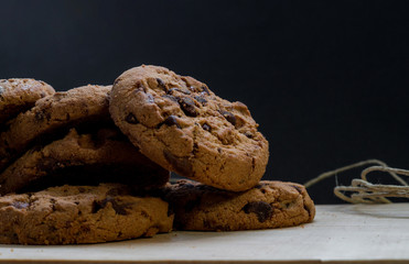 Chocolate cookies on a wooden cutting board. Black background.