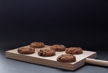 Chocolate cookies on a wooden cutting board. Black background.

