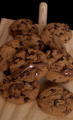 Chocolate cookies on a wooden cutting board. Black background.
