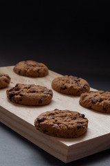 Chocolate cookies on a wooden cutting board. Black background.
