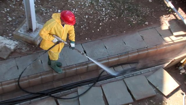 Professional is cleaning cable conduct with high pressure hose