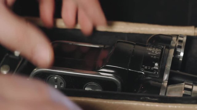 Man open bag and pulls out 8mm old film camera close-up