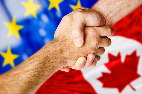 Hands shaking over Canadian and European flags symbolizing trade deal