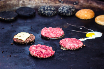 Cooking beef and pork patty with eggs and cheese for burger. Meat roasted on fire barbecue kebabs on the grill. Grilled burger cutlet beef minced meat patties or frikadeller in a pan. Street food. 
