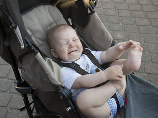 Little baby is crying in baby carriage. Stroller with unhappy li