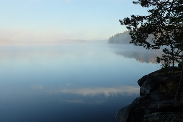 Beautiful lake view in early morning light and mist on lake surface, Finland.