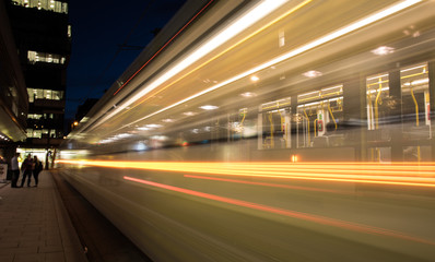 Lights of a moving tram at night.