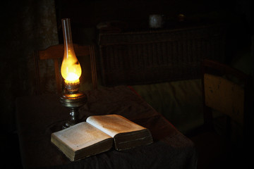 Vintage books opened for reading with ancient lamp