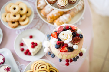 Cake with various berries and meringues on a stand.