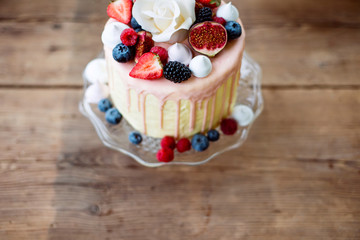 Cake with various berries, figs, meringues and rose on top.
