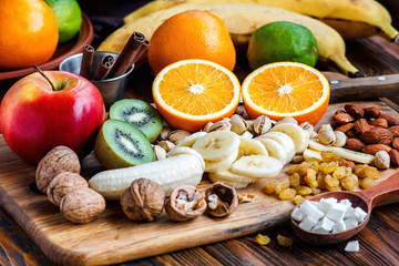 Fresh fruits. Healthy food. Mixed fruits and nuts background.Healthy eating, dieting, love fruits. Studio photography of different fruits and nuts on old wooden table. Organic Healthy Assorted Fruits. - obrazy, fototapety, plakaty