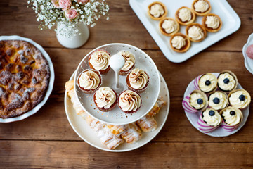 Table with cupcakes, tarts, pie and horn pastries.