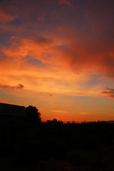 Rustic sunset in scarlet colors with dense clouds on evening sky. Vertical orientation