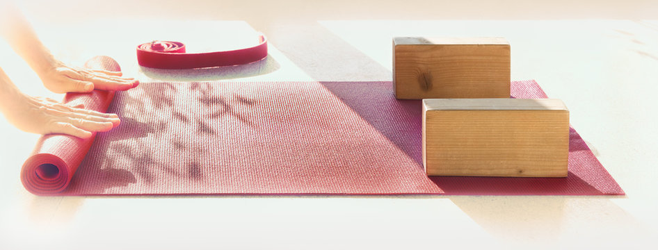 Mężczyzna przygotowuje matę i przybory do zajęć jogi.