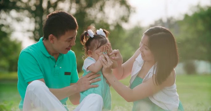 young Asian family with a year-old baby in a Park during a picnic, have fun, slow motion, close up