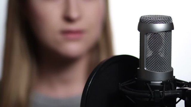 Closeup female singer recording track in studio