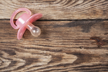 Red baby pacifier  on wood background , top view