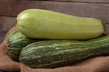 green zucchini and courgettes on sackcloth  wooden background