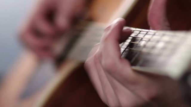 Man's fingers playing on guitar frets