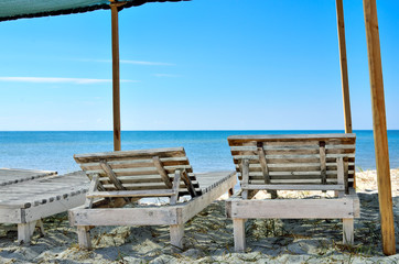 Wooden sunbeds on the background of blue sea. Resorts, vacation and seascapes.