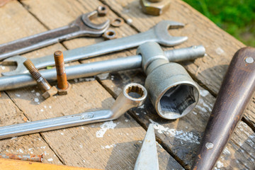 On weathered old wooden surface lie the , oily wrenches.