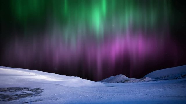 Northern Lights aurora Borealis in the snowy mountains.