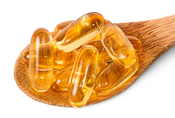 Cod liver oil omega 3 capsules on wooden spoon