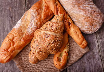 Assortment of fresh baked bread and croissants on burlap on rustic table