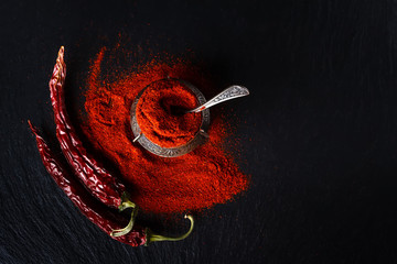 Old container for spices stuffed full of ground chili pepper. The photo in a dark key.