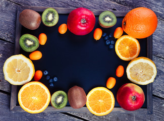 Fresh fruits oranges, kiwi, lemons, apples arranged in a group, natural still life for healthy food. Top view. Empty space for text. Colors toning