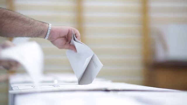 Unrecognizable people cast their vote during elections in a voting station