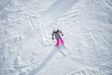 Fototapeta na wymiar Woman in colorful ski suit, skiing down the mountain.