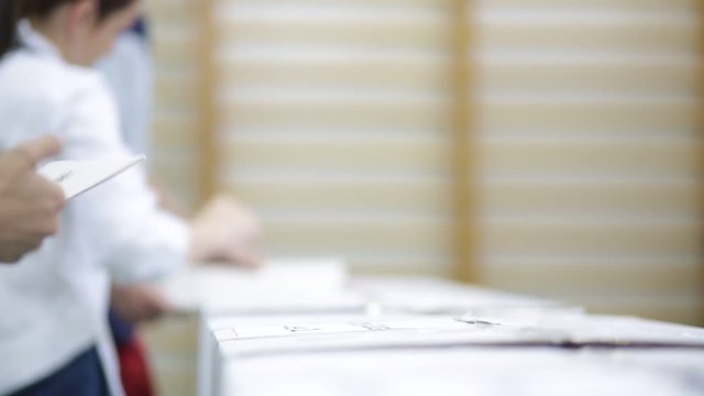Unrecognizable people cast their vote during elections in a voting station