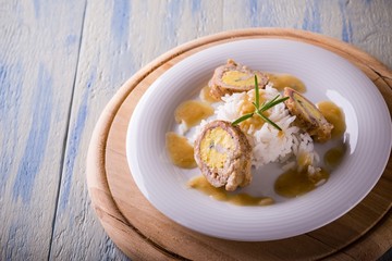 Portion of meat rolls filled by eggs and rice on white plate and wooden board