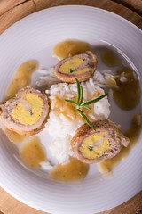 Top view on meat rolls with egg and cheese on white plate