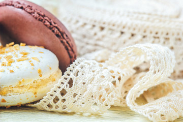 pastel colored macaroon with vintage lace ribbon on paper background