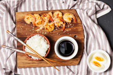 Rice with shrimp and soy sauce on a black background, horizontal, soft focus