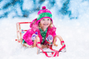 Little girl playing in snowy winter forest