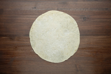 Dough for pizza on dark wood background. Top view