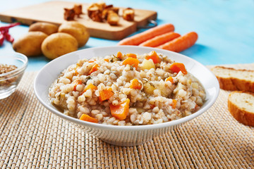 Buckwheat soup in white bowl surrounded by ingredients on wooden blue table