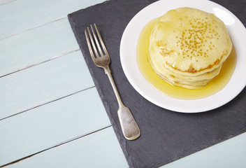 A stack of golden syrup covered pancakes on a painted breakfast table background forming a page border